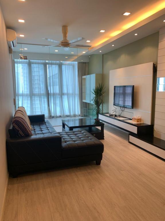 a living room with a black couch and a tv at MARC RESIDENCE BY RED HOMES in Kuala Lumpur