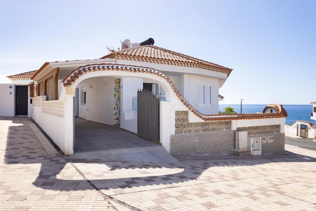 a white house with an archway next to the ocean at Coastal Hideaway in Puerto de Santiago