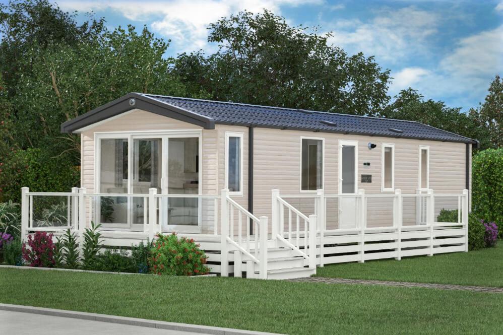 a tiny house is shown with a white fence at The Spey Van - Beautiful, luxury static caravan in Aberlour