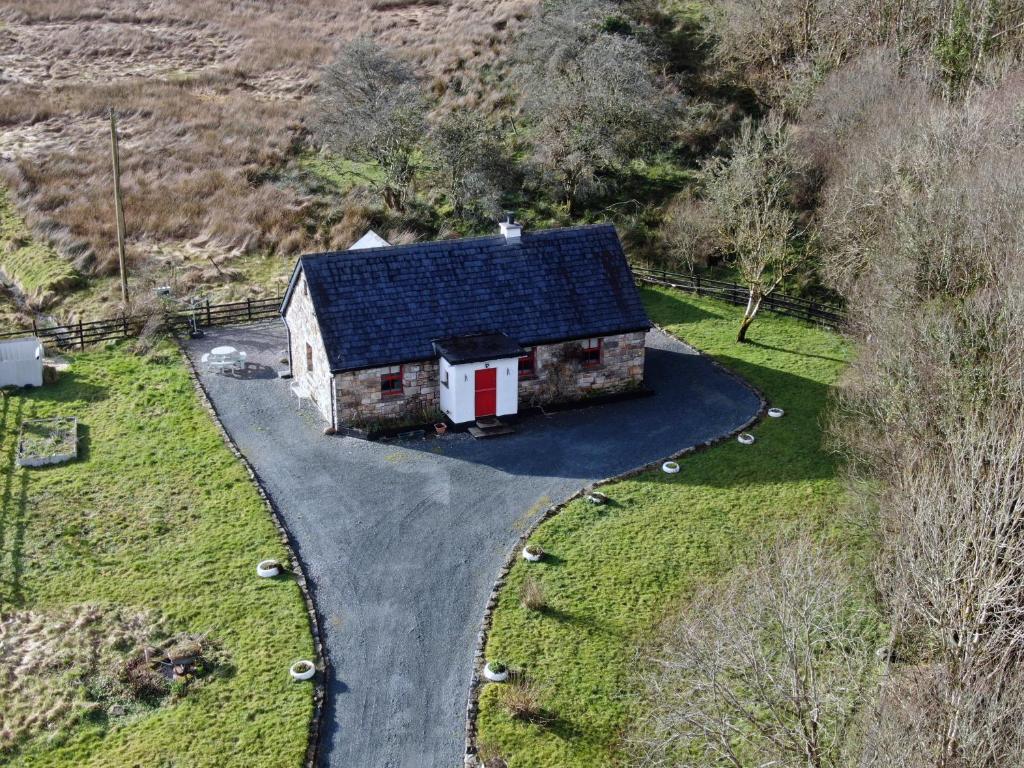 um velho celeiro com um telhado preto numa estrada em Carraun Cottage em Manorhamilton