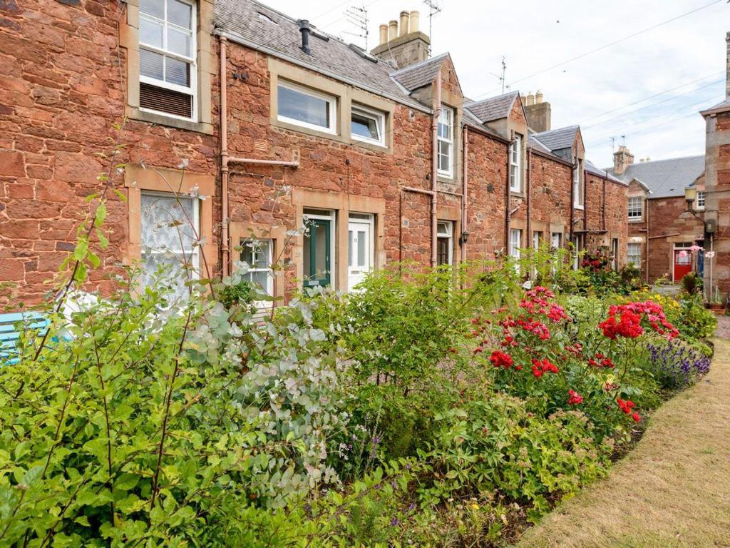 a garden in front of a brick building with flowers at Kittiwake in North Berwick