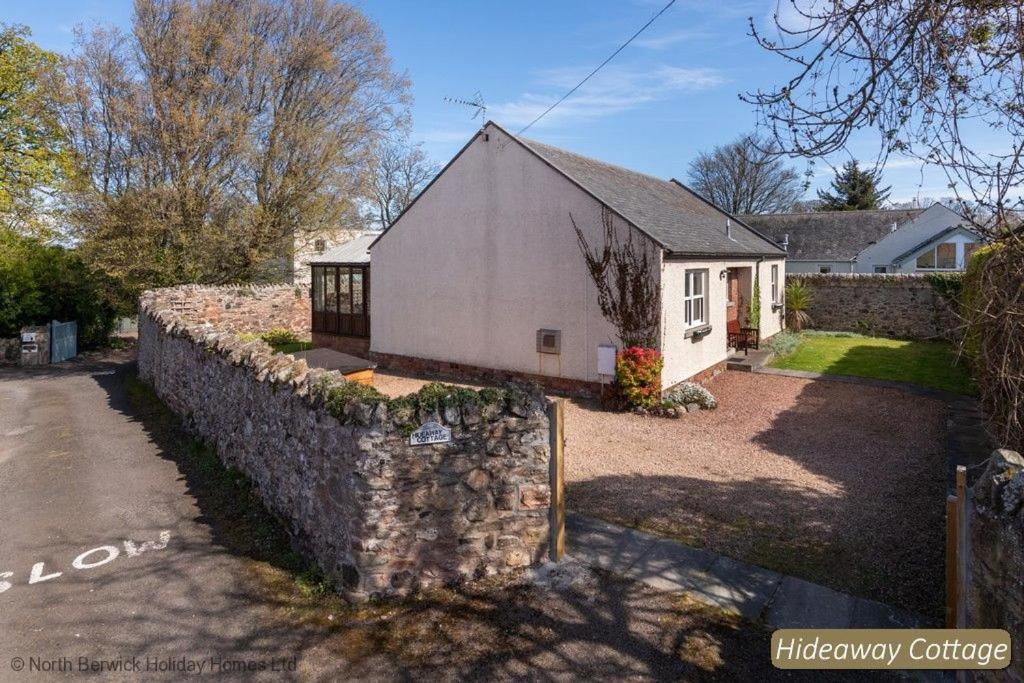 a house with a stone wall next to a building at Hideaway Cottage in Dirleton