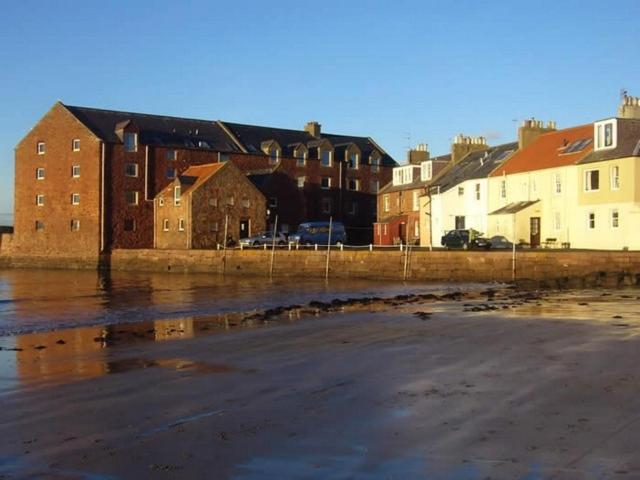 a group of buildings on the shore of a beach at Harbourside Cottage in North Berwick