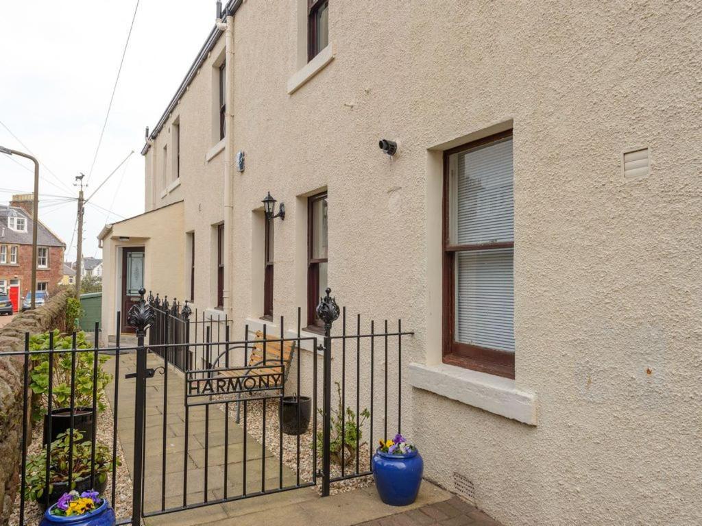 uma vedação em frente a um edifício com uma placa em Harmony Undercroft em North Berwick