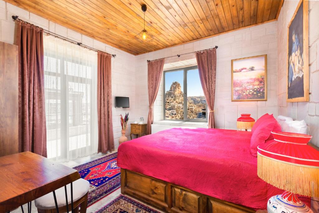 a bedroom with a red bed and a window at Cappadocia hotel Megaron cave in Ortahisar