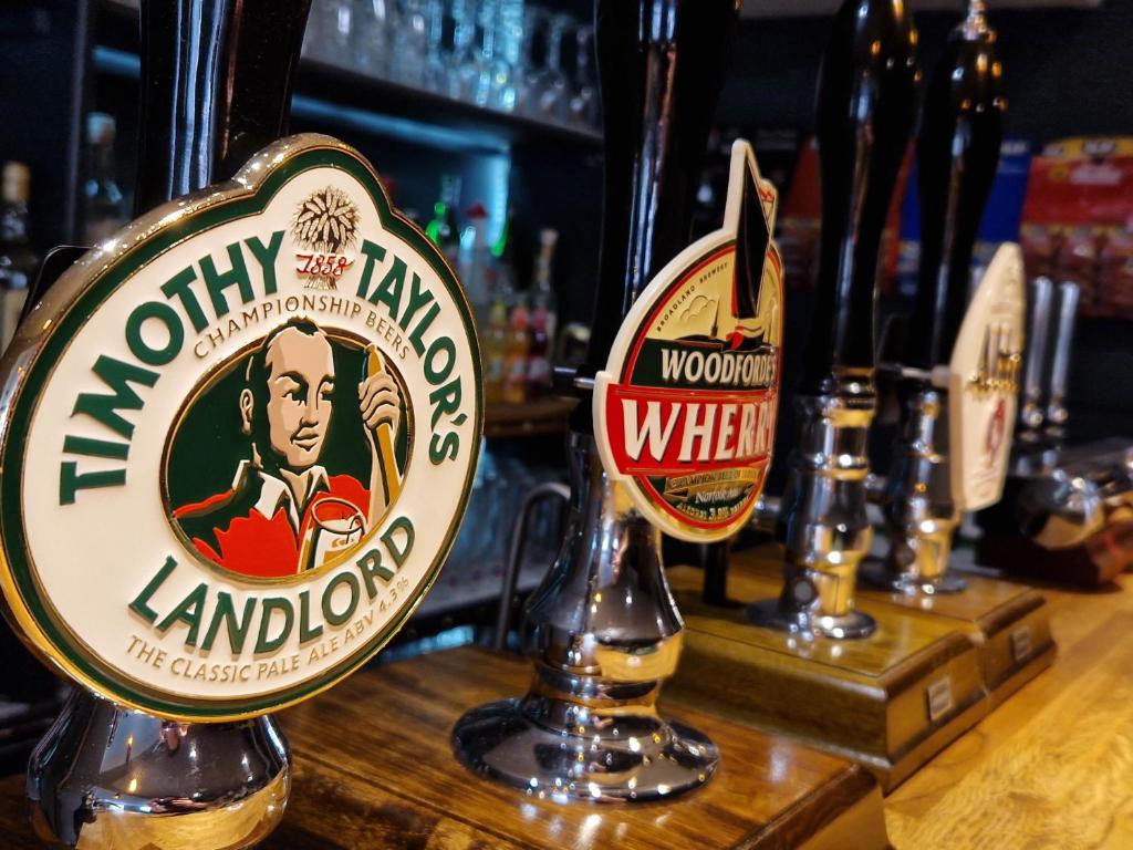 a group of beer signs on a bar at Shoulder of Mutton in Foxton