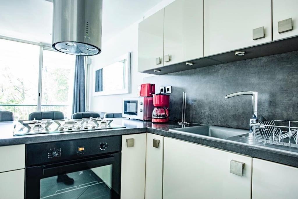 une cuisine avec des armoires blanches et un lave-vaisselle noir dans l'établissement Bleu soleil * Clim * Parking privé * Chambre * Terrasse, à La Grande Motte