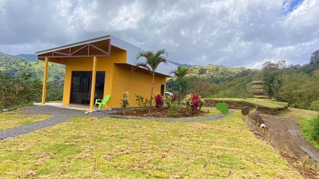 a small yellow house on top of a hill at Vulkan Arenal Amazing View Lodge 4 WD in El Castillo de la Fortuna