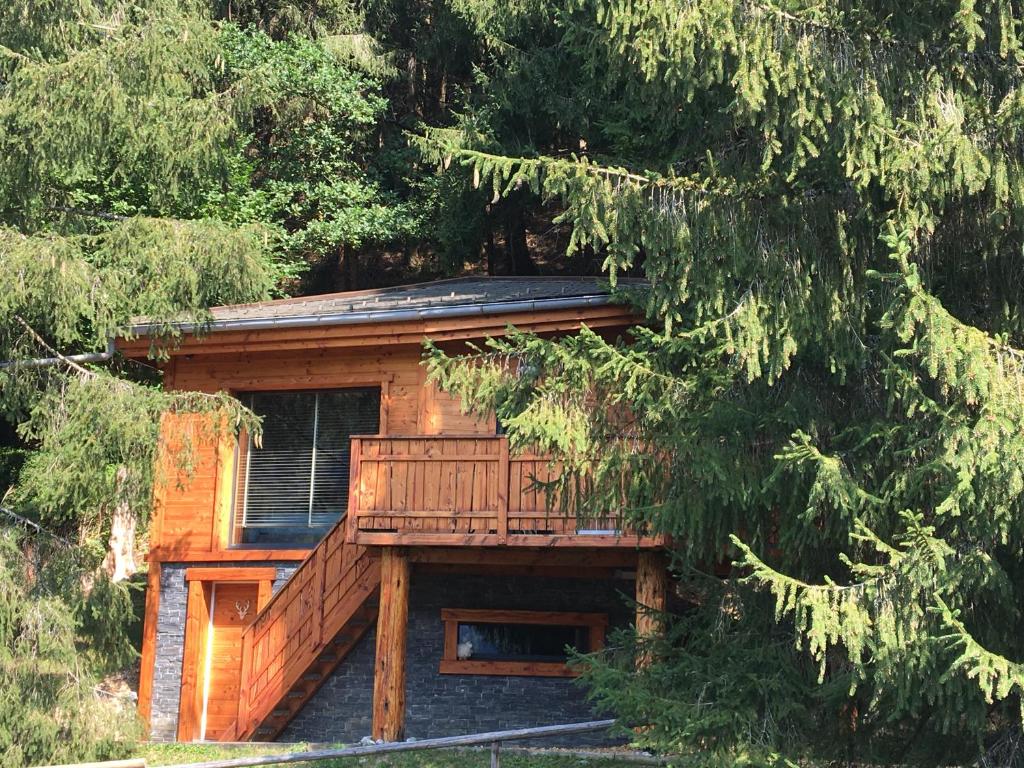 a log cabin with a deck in the woods at Chalet dans les Arbres in Saint-Jean-d'Aulps