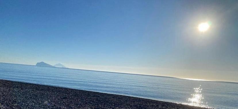 una spiaggia con il sole che sorge sull'acqua di La Casetta di Azzurra a Canneto