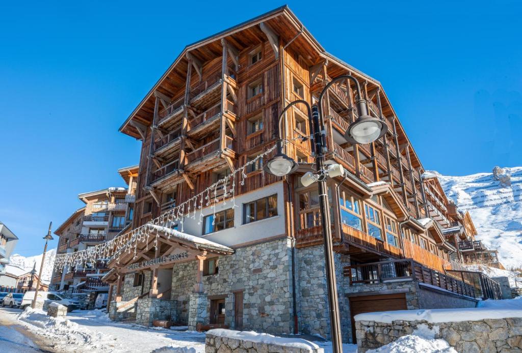 un gran edificio de madera en la nieve con luz de la calle en Hôtel L'Aiguille Percée, en Tignes