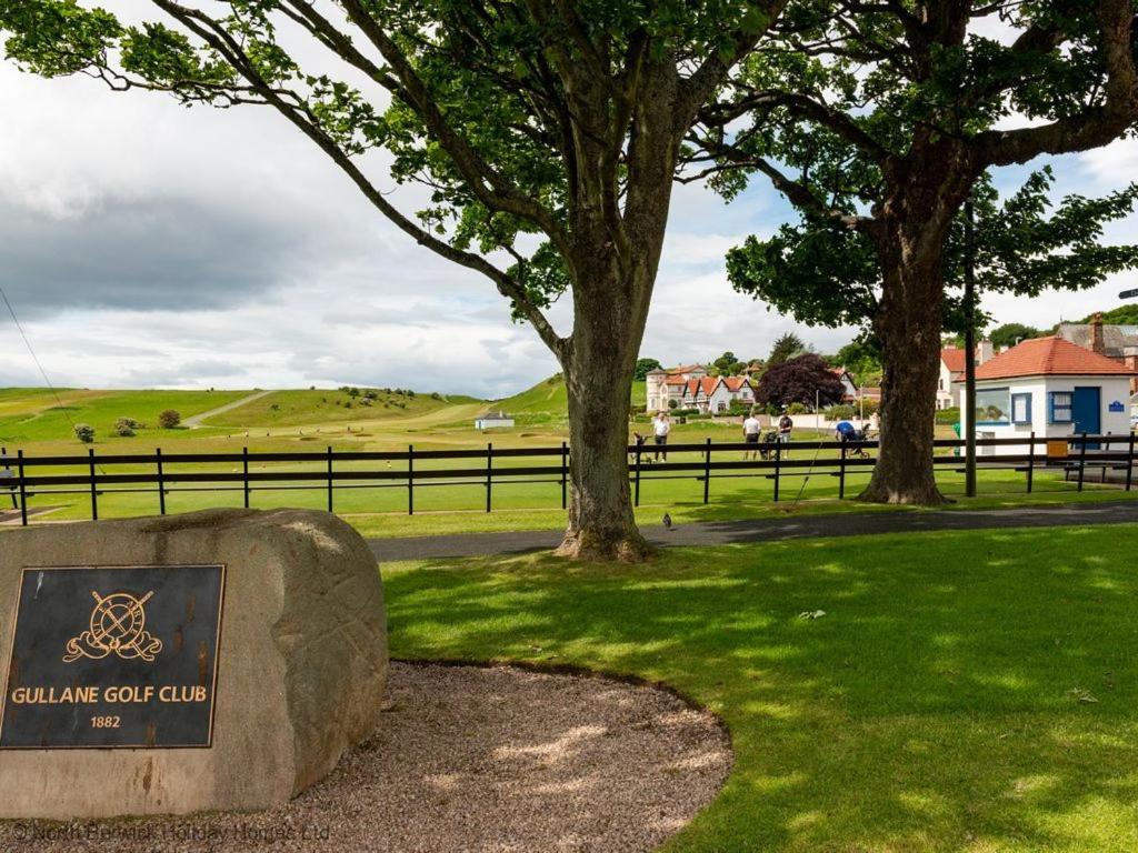 a sign on a rock in a park with trees at Rosebery Place in Gullane