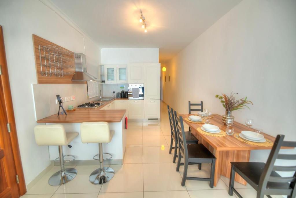 cocina y comedor con mesa de madera y sillas en Large and modern 2bedroom with balcony GLUB1-1, en Il-Gżira