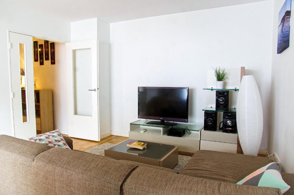 een woonkamer met een bank en een flatscreen-tv bij Belfort - Appartement 2 chambres avec ascenseur et Parking in Bordeaux