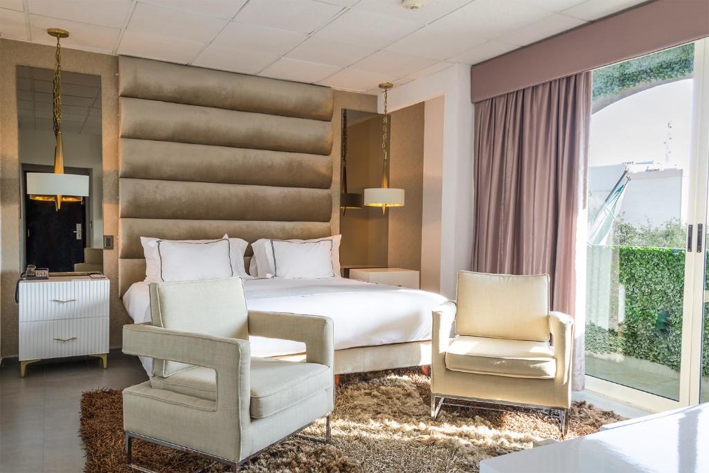 una camera con un letto bianco e due sedie di Hotel Posada San Antonio a Reynosa