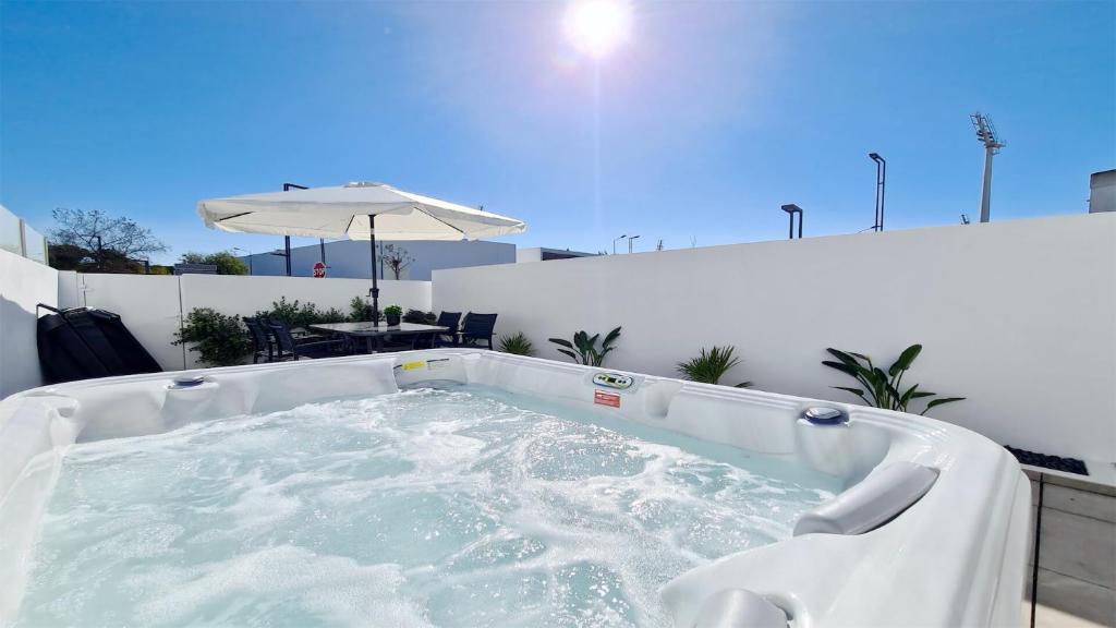 a hot tub on a patio with an umbrella at Marina Retreat - CleverDetails, for 2 adults and 2 children, Jacuzzi, near the Marina and the beach in Vilamoura