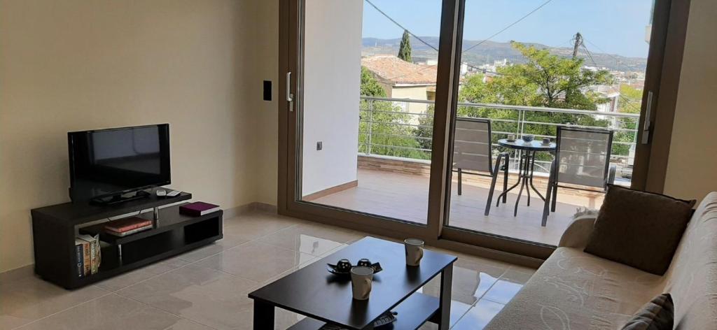 sala de estar con sofá, TV y balcón en AYRA ROOMS ALIVERI, en Aliveri