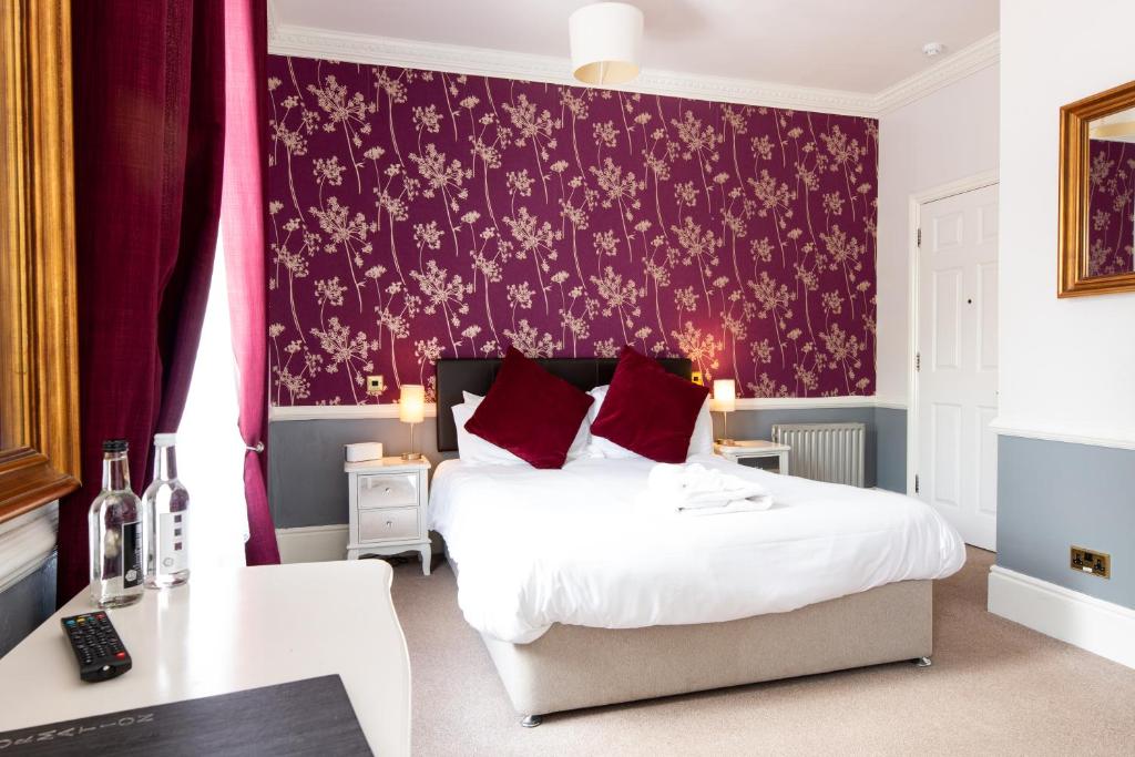 um quarto com uma cama e uma parede vermelha em Woodlands Lodge Hotel em Bartley