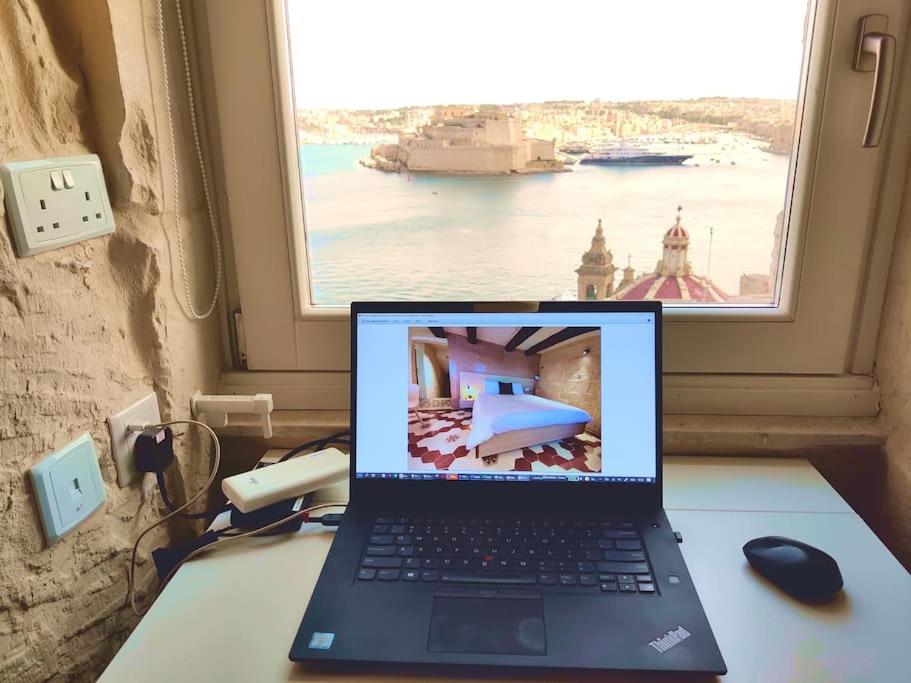 un ordinateur portable assis sur un bureau avec une fenêtre dans l'établissement Coast 52 Savynomad Harbour Residences wow Views, à La Valette