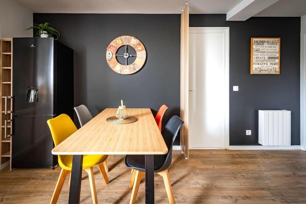 ein Esszimmer mit einem Tisch, Stühlen und einer Uhr in der Unterkunft Life&amp;Travel - Appartement Bordeaux - 4 chambres in Bordeaux