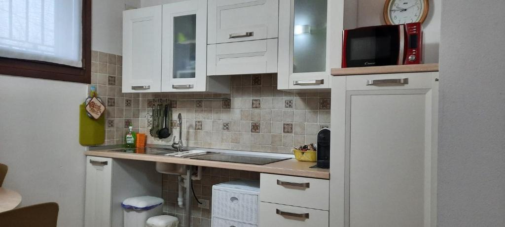 uma cozinha com armários brancos, um lavatório e um micro-ondas em Il Ghiandolino em Imola