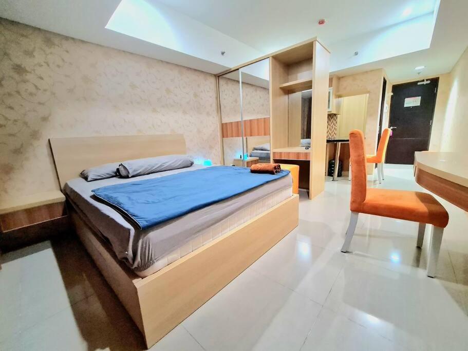 Schlafzimmer mit einem Bett, einem Schreibtisch und einem Stuhl in der Unterkunft La Grande Merdeka Apartment in Bandung