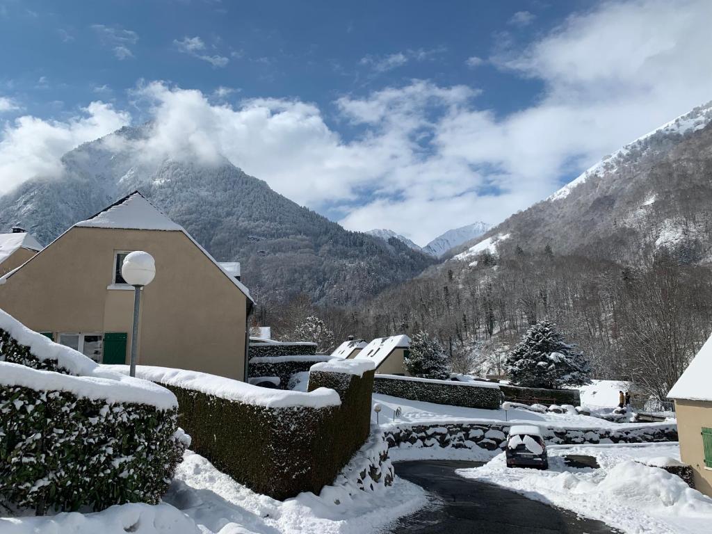 a snow covered house with a mountain in the background at Chalet tout confort 3 chambres in Cauterets