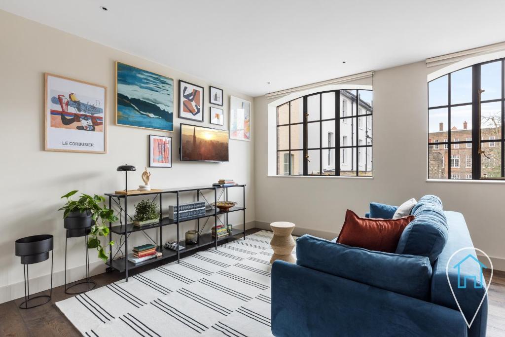 a living room with a blue couch and some windows at Modern 1BR home in Islington! in London