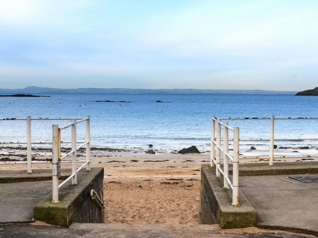 una playa con una barandilla blanca y el océano en The Nook, en North Berwick