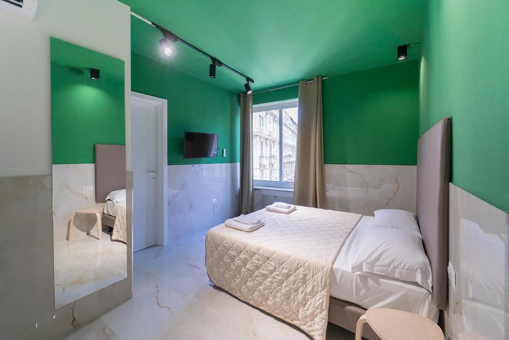 una camera da letto con pareti verdi, un letto e uno specchio di P.C. Boutique H. Vesuvius, Napoli Centro, by ClaPa Group a Napoli