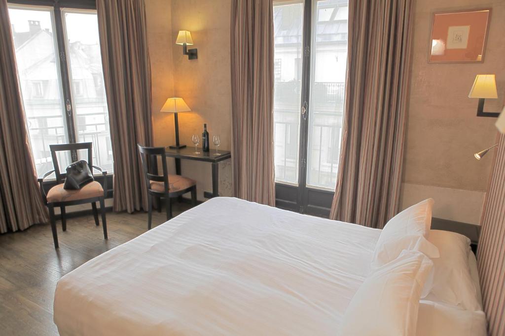 a hotel room with a bed and a desk and windows at Europe Saint Severin-Paris Notre Dame in Paris