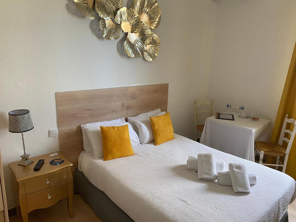 1 dormitorio con 1 cama con almohadas amarillas y reloj en la pared en Hôtel Restaurant La Plage, en Port-Saint-Louis-du-Rhône