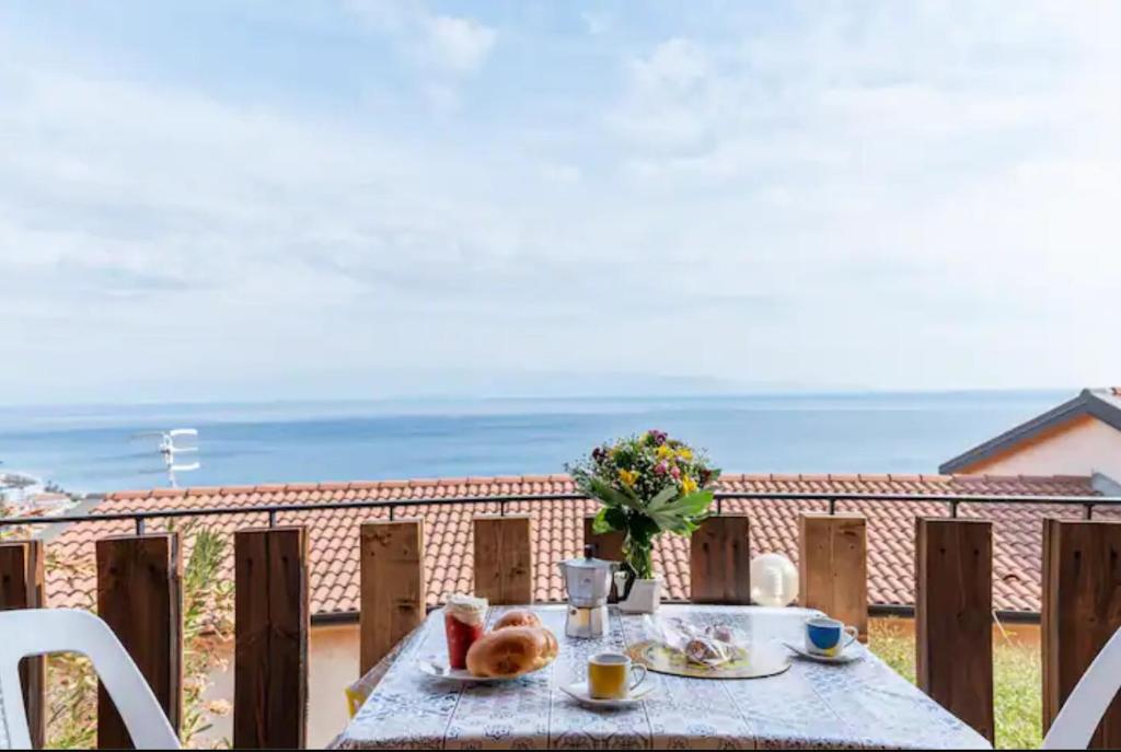 a table with food and a view of the ocean at Sant'Alessio Village in SantʼAlessio Siculo