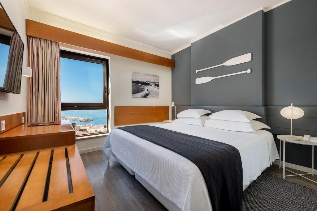 um quarto com uma cama grande e uma janela grande em Hotel Apartamento Sinerama em Sines