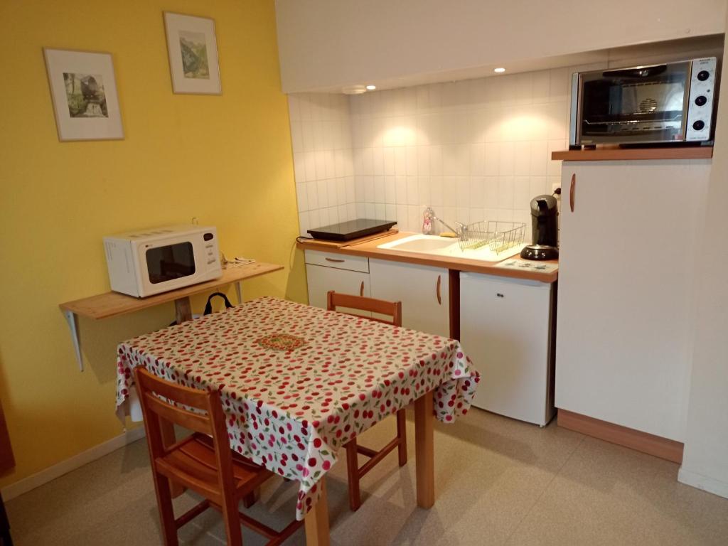 a small kitchen with a table and a microwave at Studio proche des thermes en rez-de-chaussée avec place de parking in Bagnères-de-Bigorre
