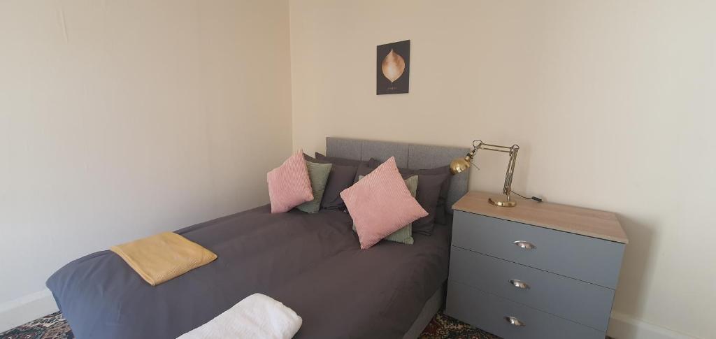 ein Schlafzimmer mit einem Bett mit rosa Kissen und einem Nachttisch in der Unterkunft Coventry Park House in Parkside