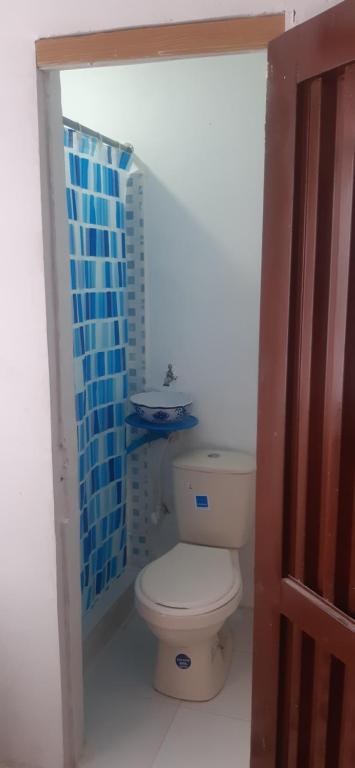 baño con aseo y pared de azulejos azules en Hostal la 18, en Pereira