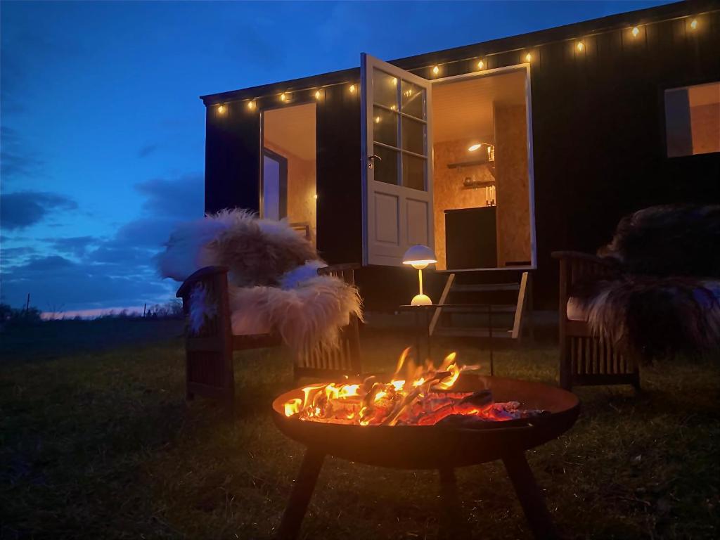 una hoguera frente a una casa por la noche en Cozy Tiny House on a farm, en Skibby