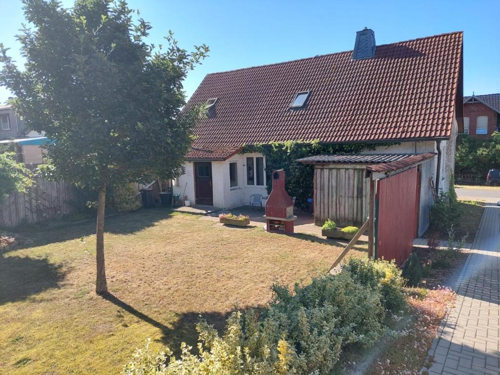 uma pequena casa com um quintal com uma árvore em Altmark - Haus am Hang mit Garten 