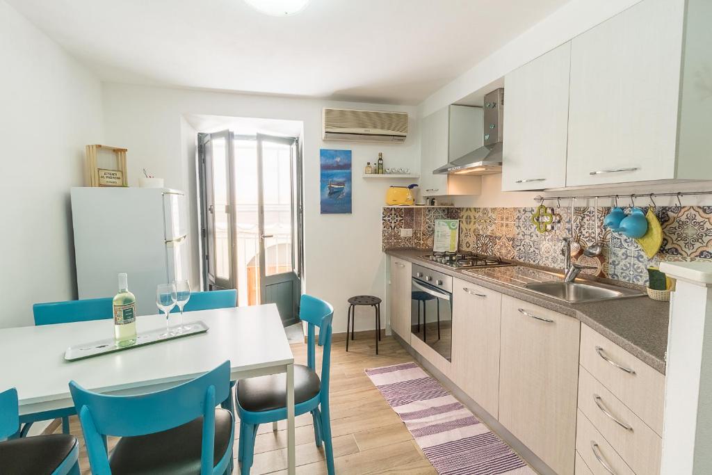 een keuken met een tafel en blauwe stoelen in een kamer bij Apartment Veterani in Cefalù