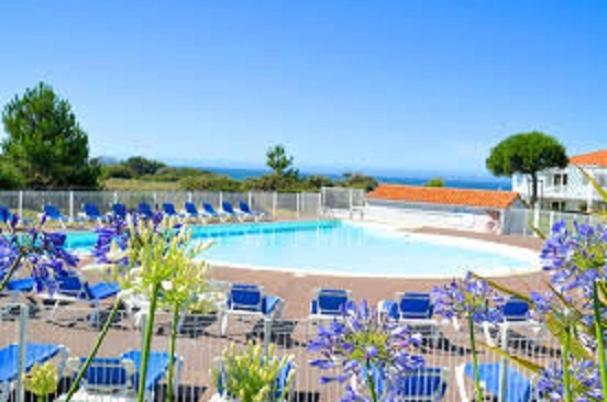 une grande piscine avec des chaises longues bleues dans l'établissement Appartement forever, à Les Sables-dʼOlonne