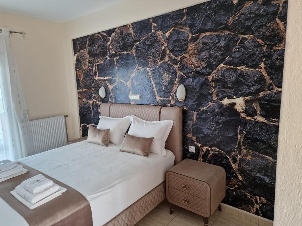 a bedroom with a large bed with a stone wall at Pension Delfini in Asprovalta