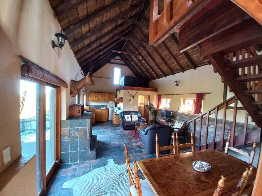 a kitchen and living room with wooden ceilings and a table at Fijnbosch Self Catering Chalet in Jeffreys Bay