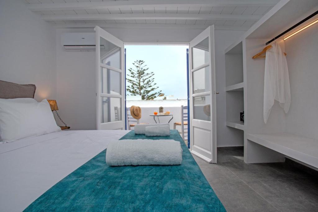 a white bedroom with a large bed with a blue rug at Aelia Suite I / Mykonos Town in Mikonos