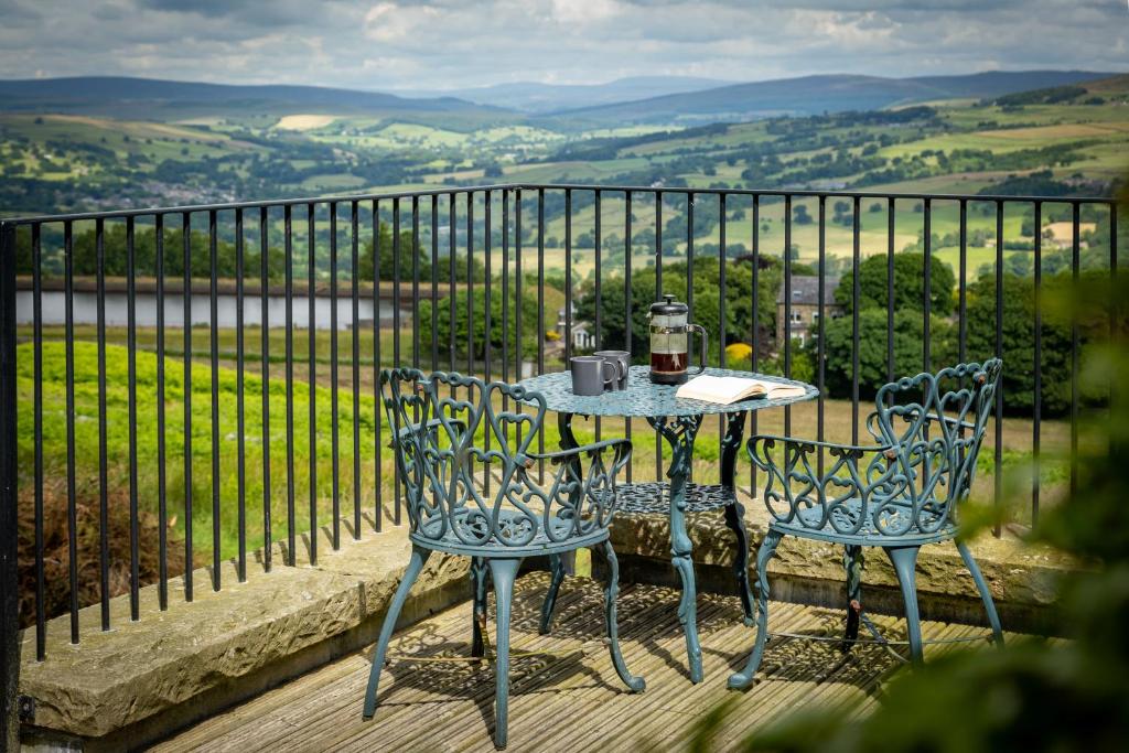 a table and chairs on a balcony with a view at Silver Well Cottage in Ilkley