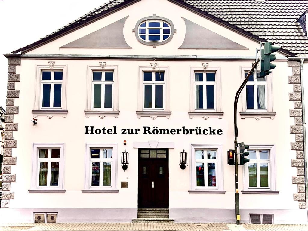 Hotel zur Römerbrücke في نيوفيد: مبنى ابيض وباب اسود واضاءة الشارع