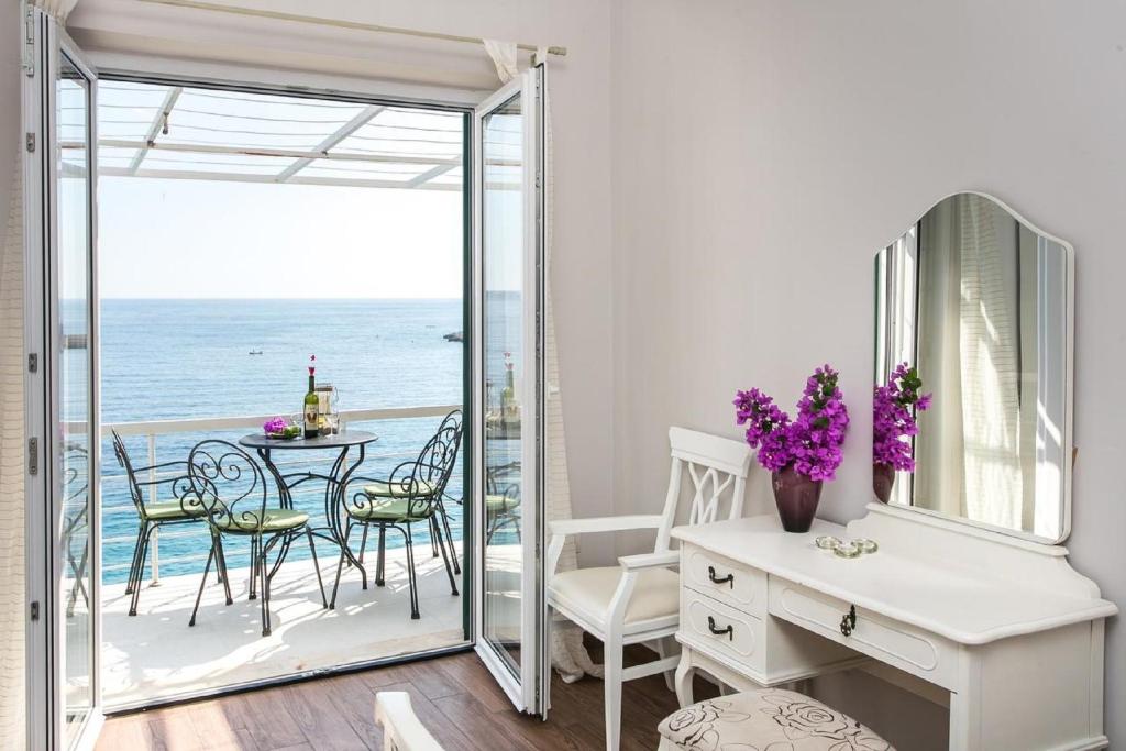 a room with a table and chairs and a balcony with the ocean at Apartments Villa Mirjana in Mlini