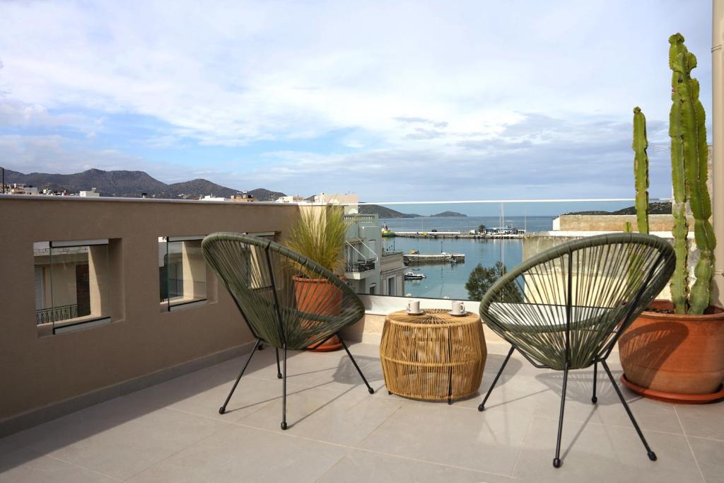 een balkon met 2 stoelen en uitzicht op een haven bij St. Nicolas Soho Apartments in Agios Nikolaos