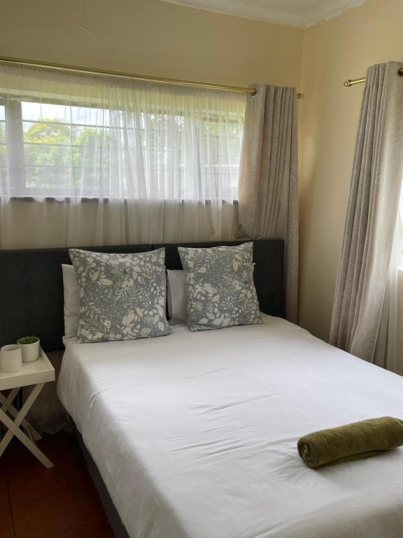 a bed with white sheets and pillows in a bedroom at 25 Swallow Yellowood in Durban