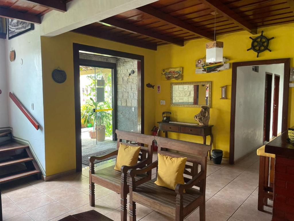 a living room with a bench and a yellow wall at Pousada Do Suiá in Arraial do Cabo